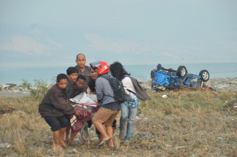 VICTIM. Residents carry a victim after after the earthquake-tsunami in Palu. Photo by Muhammad Rifki/AFP  