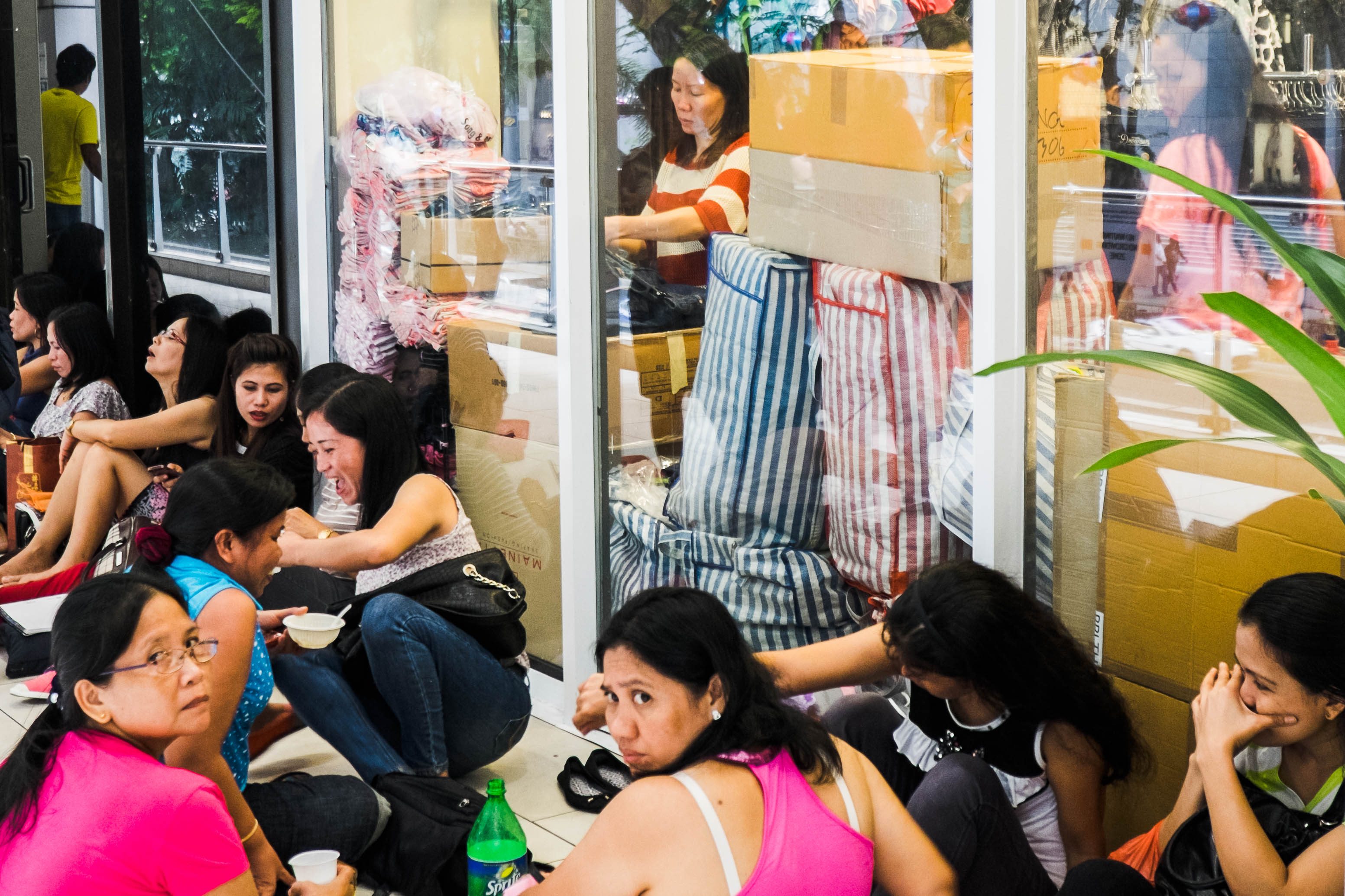 Overseas Filipino Workers sit on the floor of one of Lucky Plaza's balconies where many OFWs share meals during their day-off. 