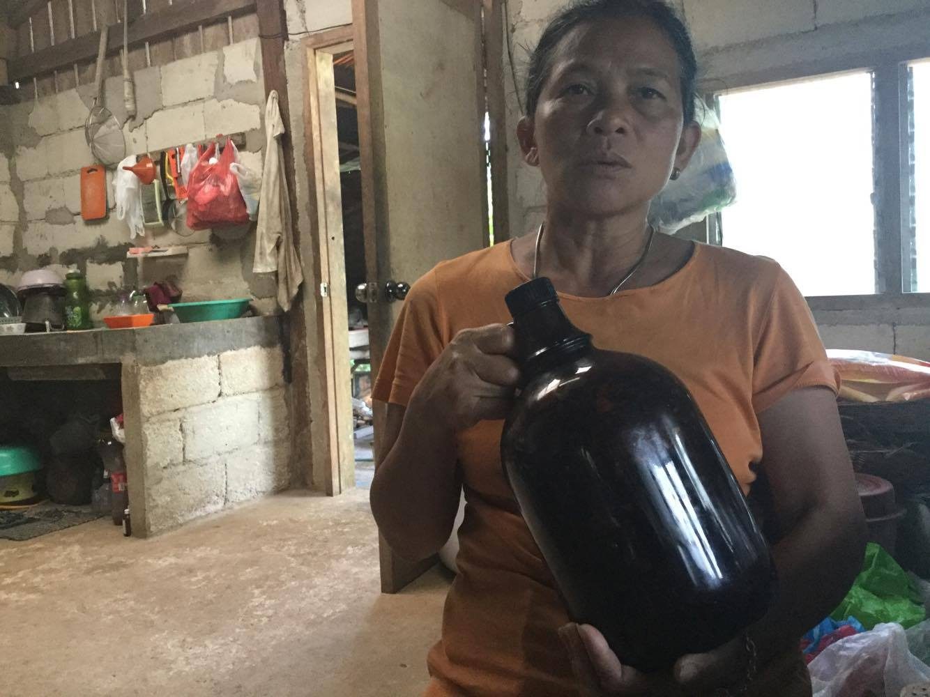 IN HER FATHER'S FOOTSTEPS. Juanita holds up the 50-year-old demijuana owned by her late father, Pedro Tumapon, one of the foremost mananambals in Siquijor 