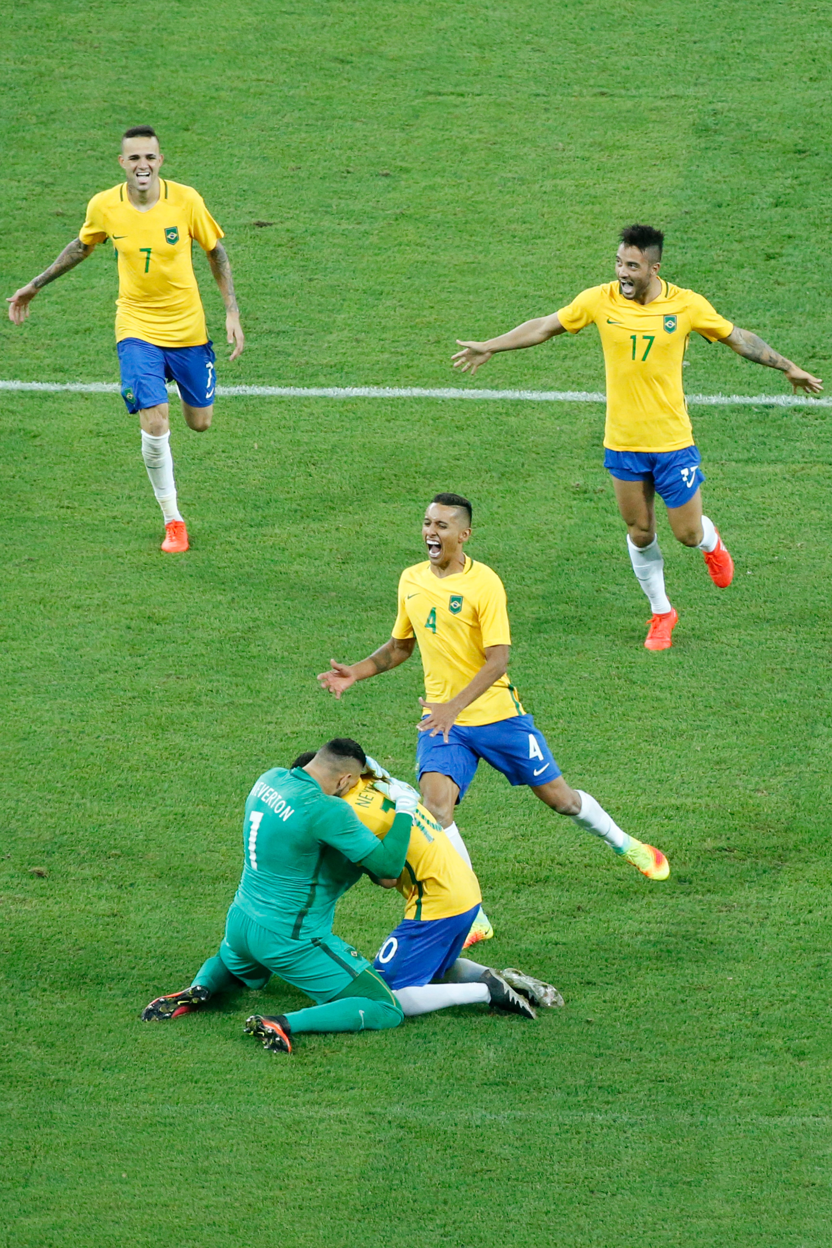Pemain timnas Brasil berlari ke arah Neymar (bawah) setelah ia mencetak gol dalam adu penalti pada final sepak bola putra melawan Jerman. Foto oleh Michael Reynolds/EPA 