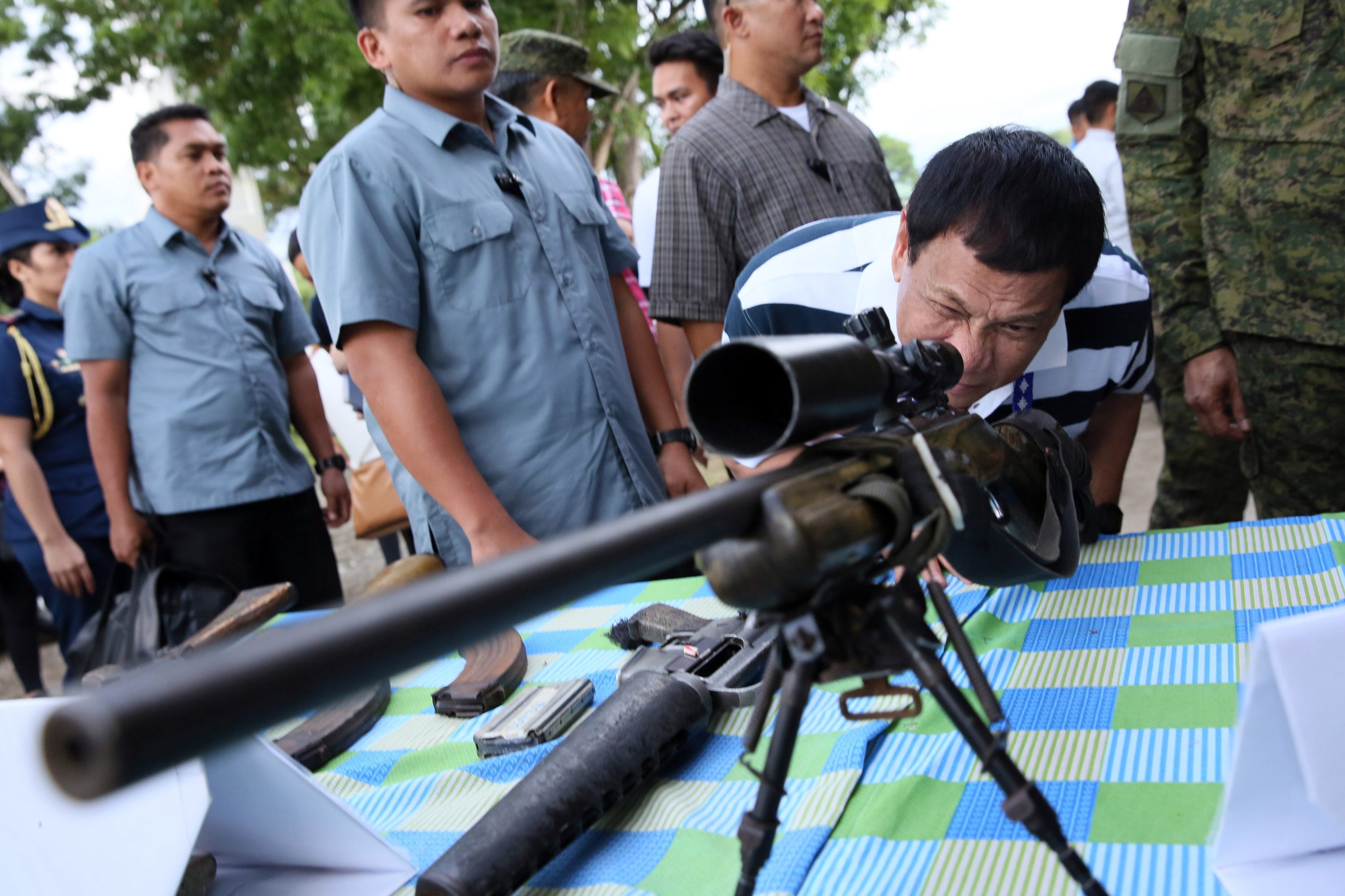 SNIPER'S VIEW. President Rodrigo Duterte peers through the scope of a sniper rifle at the inspection of firearms recovered by troops of the 4th Infantry Division in Butuan City on June 17, 2017. Photo by Robinson Ninal Jr/Presidential Photo  
