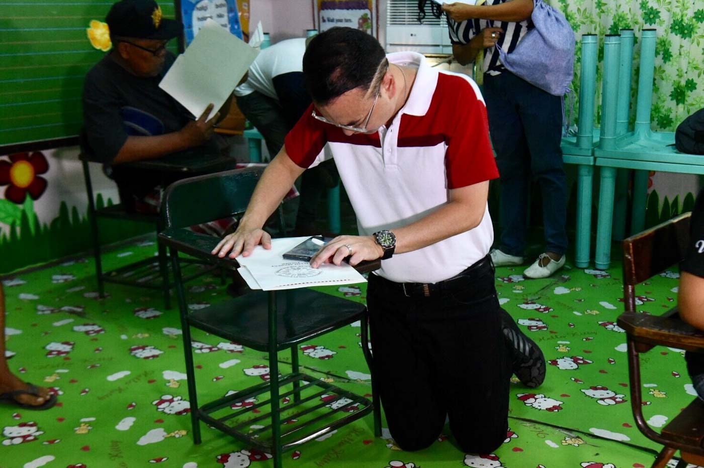 GIVING THANKS. Former Foreign Affairs Secretary and Taguig 1st District candidate for Congress kneels after filling up his ballot at the CP Sta. Teresa Elementary School. Photo by Angie de Silva/Rappler   