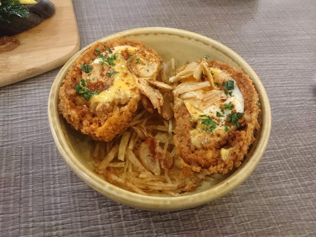 HUEVOS RELLENOS. These eggs are coated in a chorizo-breadcrumb crust and served on a bed of shoestring potatoes. 