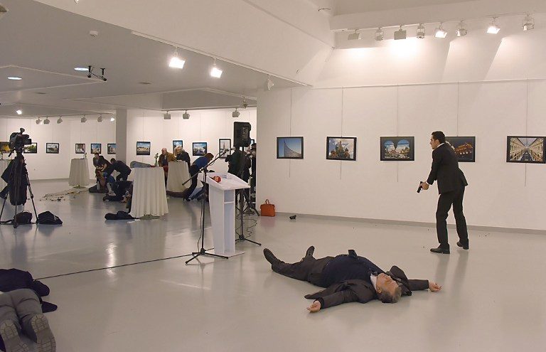 AMBASSADOR DOWN. This picture taken on December 19, 2016 shows Andrey Karlov (2ndR), the Russian ambassador to Ankara, lying on the floor after being shot by a gunman (R) during an attack during a public event in Ankara. Stringer/AFP 
