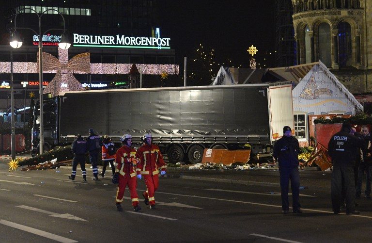 Emergency workers pass by the truck that crashed into a Christmas market in Berlin, on December 19, 2016 killing at least 12 people and injuring at least 50 people. Odd Andersen/AFP 
