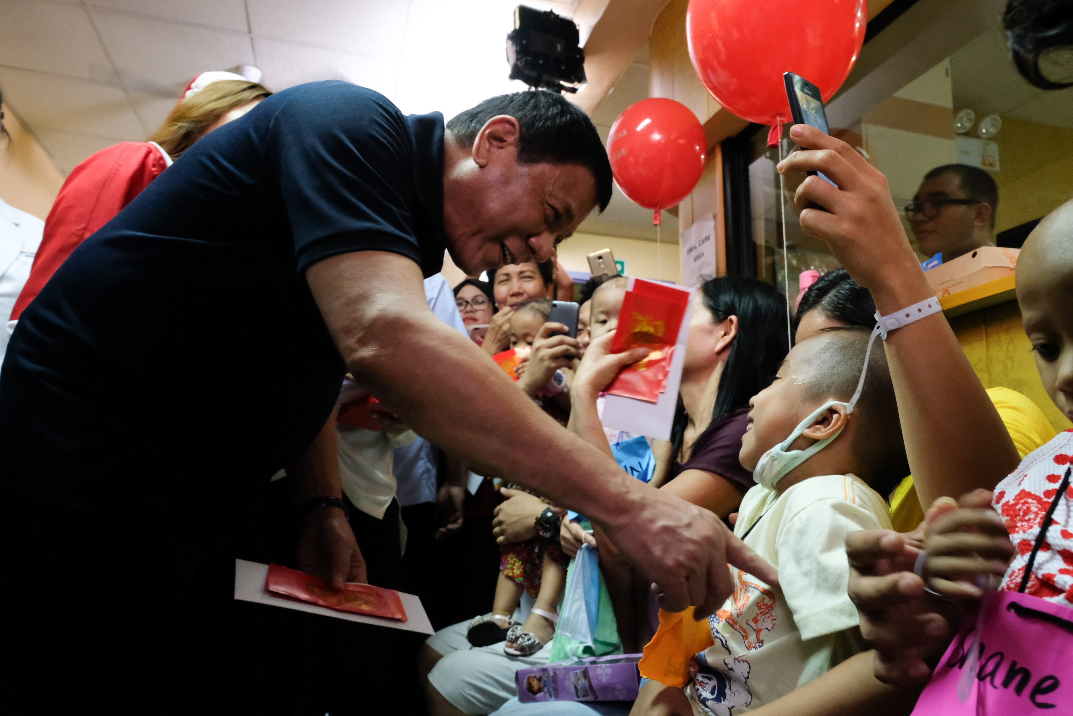 FUN SIDE. President Rodrigo Duterte tickles a cancer-stricken child while giving out Christmas presents. Photo by King Rodriguez/Presidential Photo 