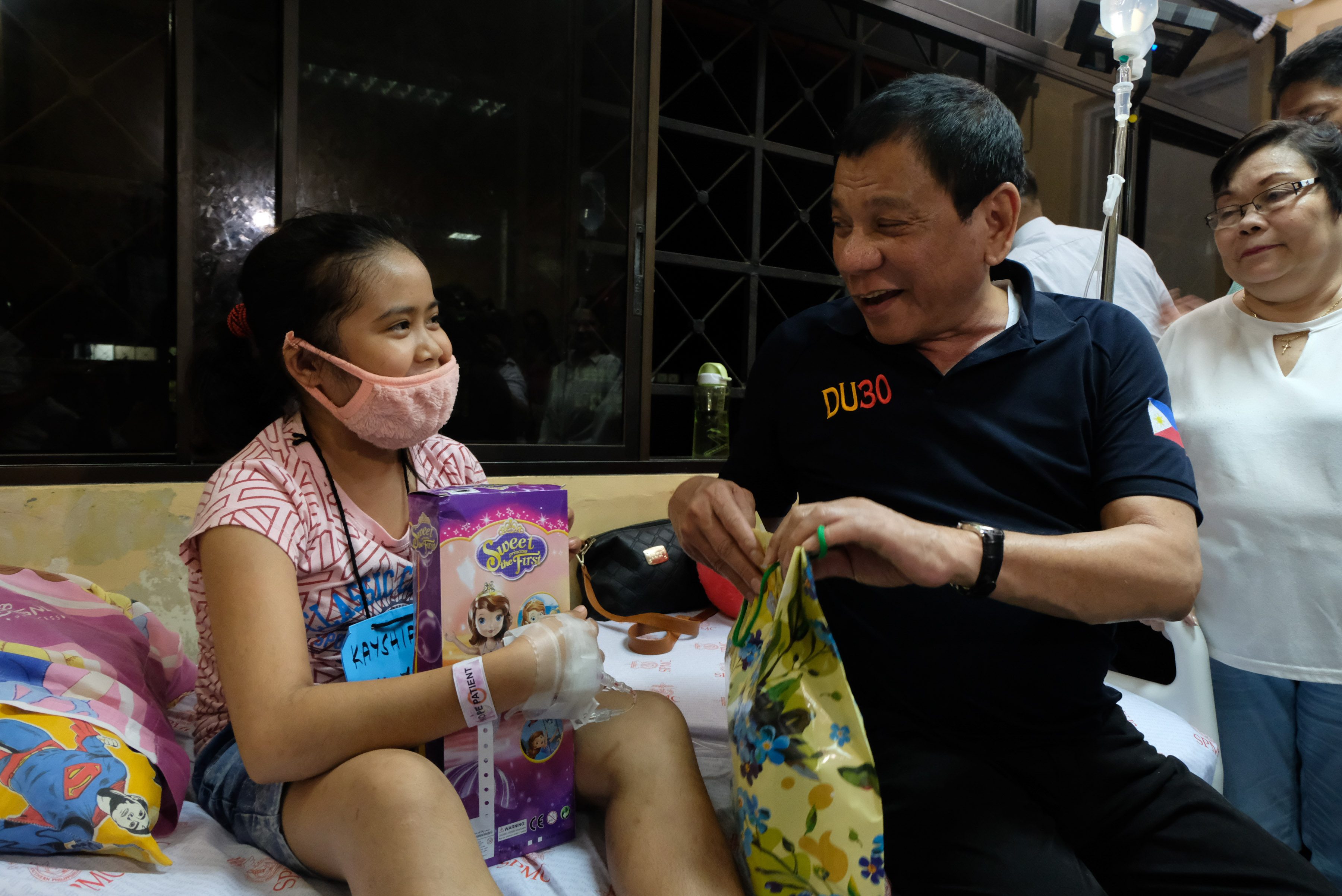 PLAYING SANTA. President Rodrigo Duterte gives a Christmas present to a cancer-stricken child. Photo by King Rodriguez/Presidential Photo 