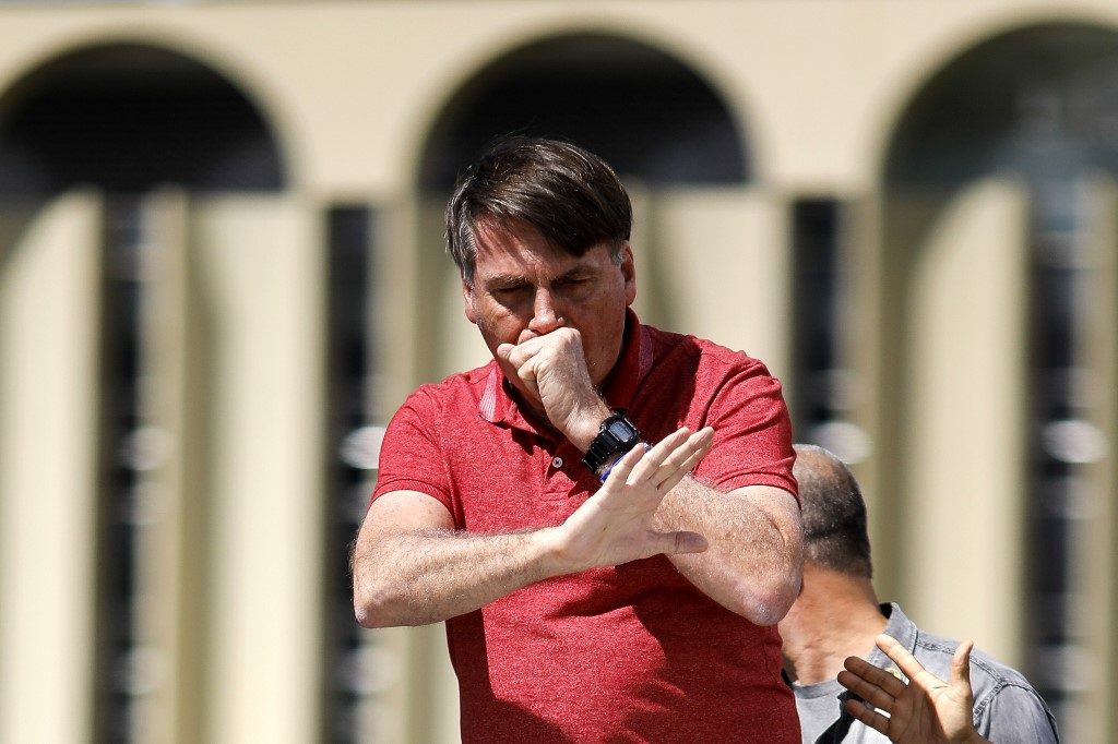 COUGHING. Brazilian President Jair Bolsonaro coughs as he speaks after joining his supporters who were taking part in a motorcade to protest against quarantine and social distancing measures to combat the new coronavirus outbreak in Brasilia on April 19, 2020. Photo by Sergio Lima/AFP 
