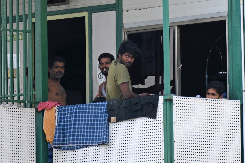 WORKERS' DORMS. Men look out from a dormitory used by foreign workers at Cochrane Lodge 2, which has been made an isolation area to prevent the spread of the COVID-19 coronavirus, in Singapore on April 15, 2020. Photo by Roslan Rahman/AFP  