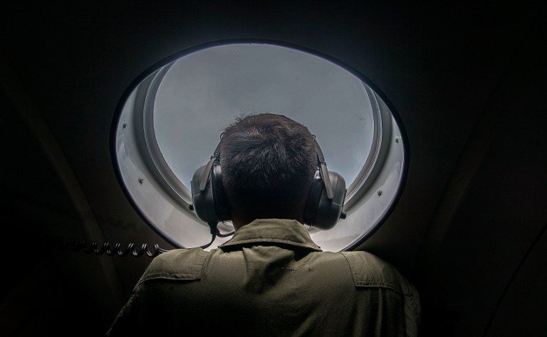 A member of the Indonesian military looks out of the window during a search and rescue for the missing flight over the waters of the Java Sea on December 29, 2014.  Photo by AFP