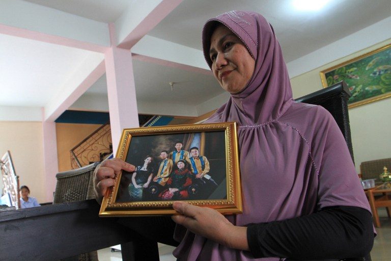 Rohana, the mother of Khairunisa, a flight attendant, points towards her daughter within a framed family photograph in Palembang, South Sumatra, on December 28, 2014.   Photo by AFP