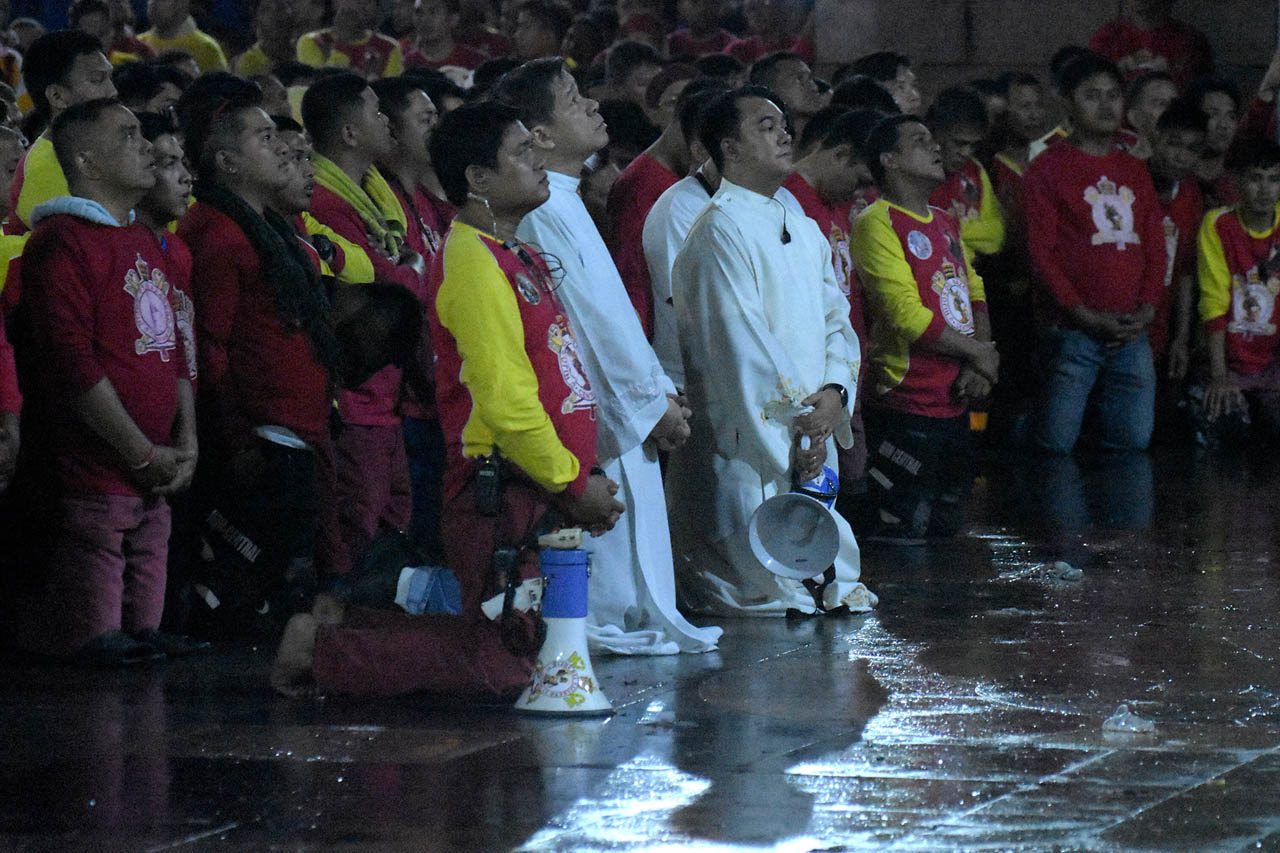 PRAYER. Parish priest Monsignor Ding Coronel and assistant parish priest Fr Douglas Badong kneel in prayer with other devotees in front of Minor Basilica of the Black Nazarene or Quiapo Church before the procession midnight of December 31, 2018. Photo by Angie de Silva  