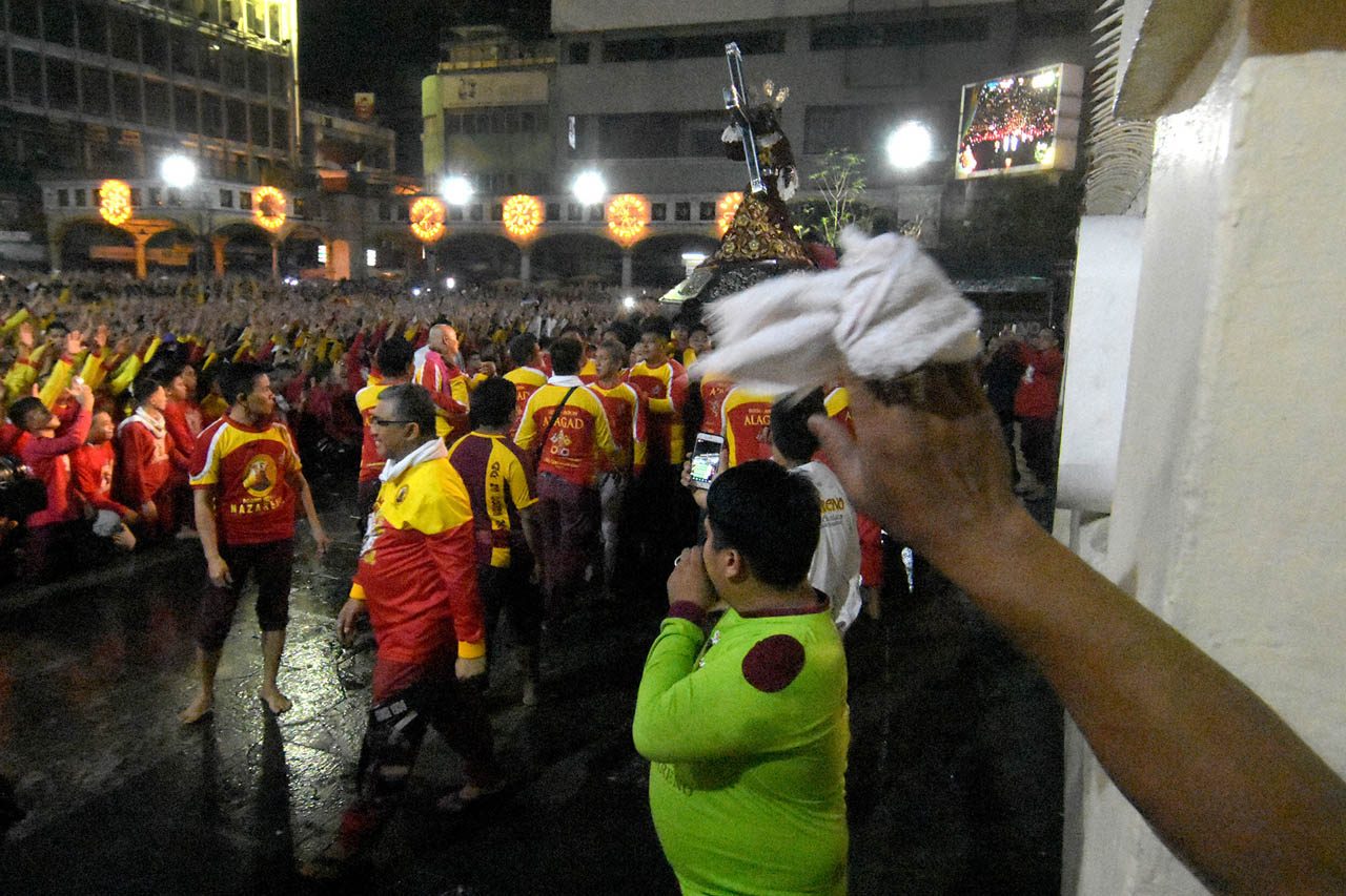 BLESSING. A devotee swirls a small white towel before the image of the Black Nazarene. Photo by Angie de Silva  
