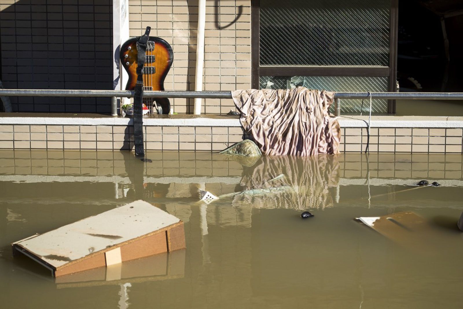 A bass guitar and floating debris are seen by a residential block as floodwaters recede in the aftermath of Typhoon Hagibis in Kawasaki on October 13, 2019. Photo by Odd Andersen/AFP 