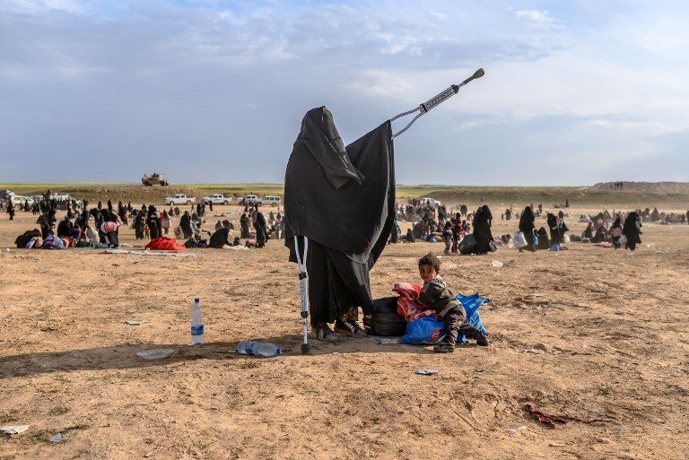 LEAVING HOME. A woman in crutches stands beside  a child as evacuees from the Islamic State group's embattled holdout of Baghouz arrive at a screening area held by the US-backed Kurdish-led Syrian Democratic Forces in Deir Ezzor on March 5, 2019. Photo by Bulent Kilic/AFP   