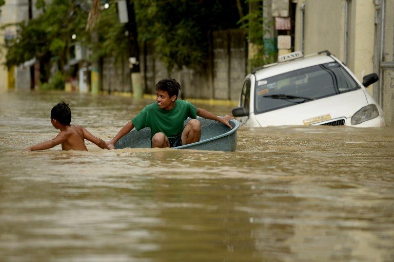 Children use a water basin to cross a flooded street in Candaba, Pampanga, north of Manila on December 18, 2015. Vast swathes of farmlands inundated by Typhoon Koppu in October were flooded again this week by rains from Typhoon Melor and the flooding could worsen or spread to other areas as a second storm in less than a week threatens the country. AFP PHOTO / NOEL CELIS / AFP / NOEL CELIS 
