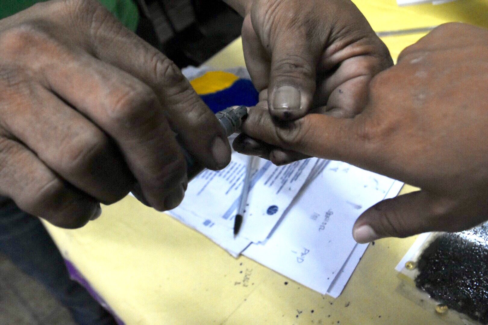 INDELIBLE INK. An election officer applies an indelible ink to a voter after casting his vote at Bagong Silang Elementary School, Caloocan City. Photo by Angie de Silva/Rappler 