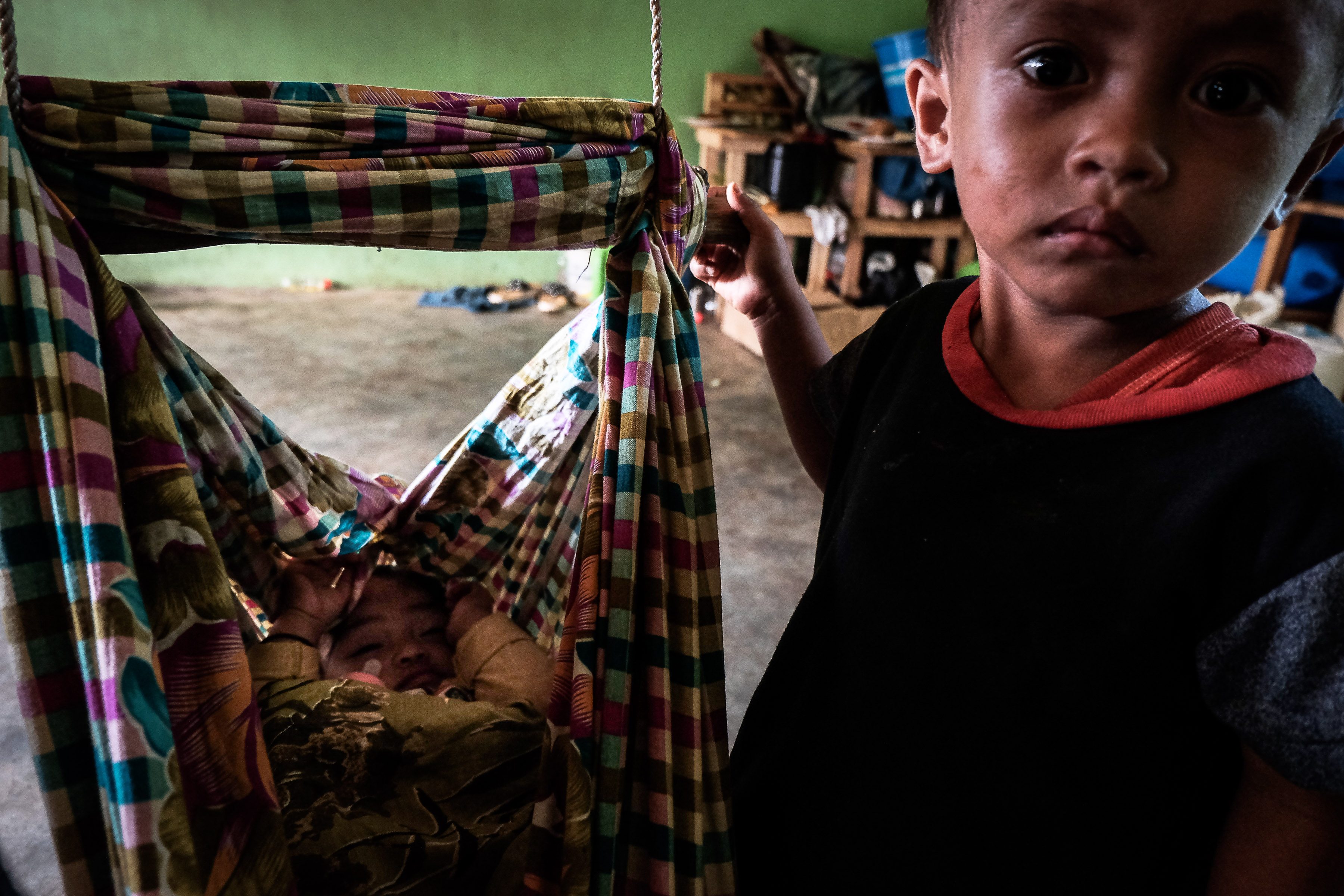A boy watches over his brother in makeshift hammock inside a wornout classroom that serves as their evacuation center in in Barangay Bubong, Pantao Ragat, Lanao del Norte.  