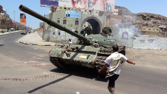IN ACTION. A photograph made available 06 April 2015 shows a man standing beside a tank drove by tribal militiamen loyal to Yemeni President Abdo Rabbo Mansour Hadi during clashes with Huthi fighters in the southern port city of Aden, 05 April 2015. Stringer/EPA 