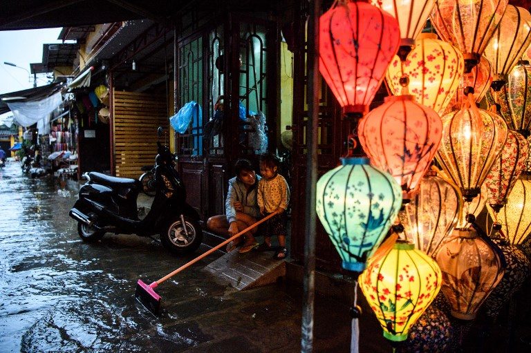 VIETNAM FLOODING. A mother and her child sit in their house entrance next to a lantern shop in the town of Hoi An on November 8, 2017 following days of heavy rains after Typhoon Damrey hit the coast. Photo by Anthony Wallace/AFP 