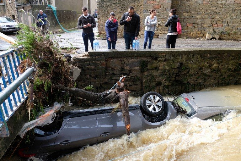 FRANCE FLOODING. Residents look at damaged cars on the Trapel river following heavy rains that saw rivers bursting banks on October 15, 2018 in Villegailhenc, near Carcassone, southern France. Photo by Eric Cabanis/AFP  