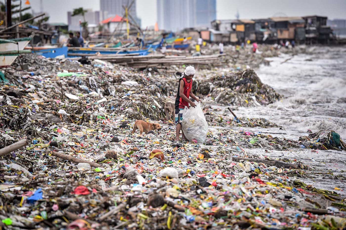 ENTERPRISING. A resident of Baseco, Manila, salvages recyclables from the trash washed ashore by wave surges from Manila Bay. Photo by Alecs Ongcal/Rappler   