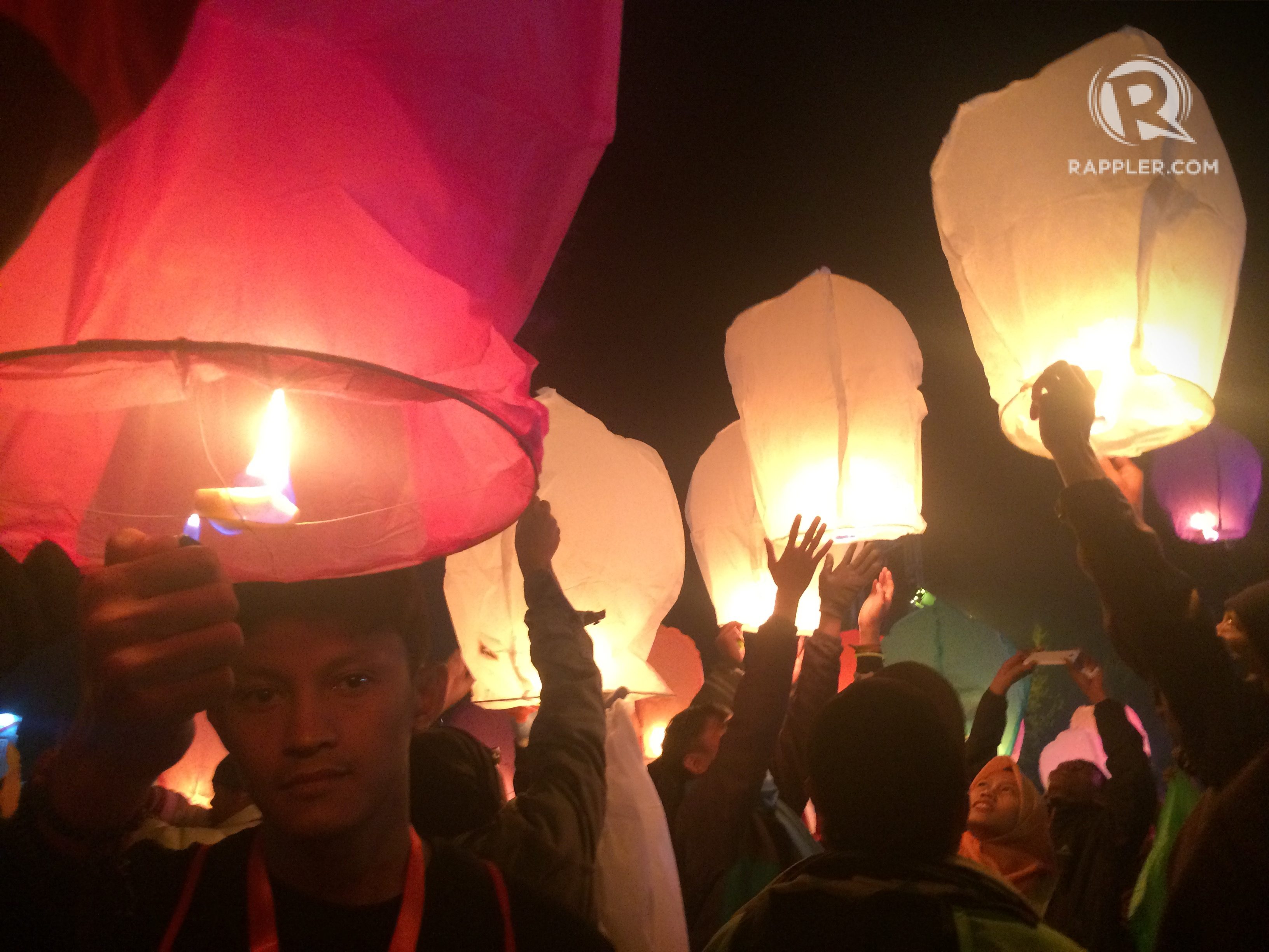 Seorang pengunjung menyalakan lampion di malam puncak Dieng Culture Festival. Foto oleh Nadia Vetta Hamid/Rappler 