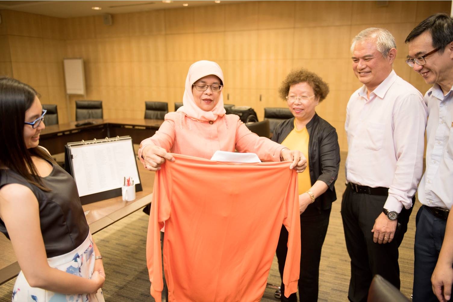 PERSATUAN. Presiden Singapura terpilih Halimah Yacob memegang kemeja berwarna orange yang melambangkan persatuan. Foto diambil dari akun Facebook Halimah Yacob 