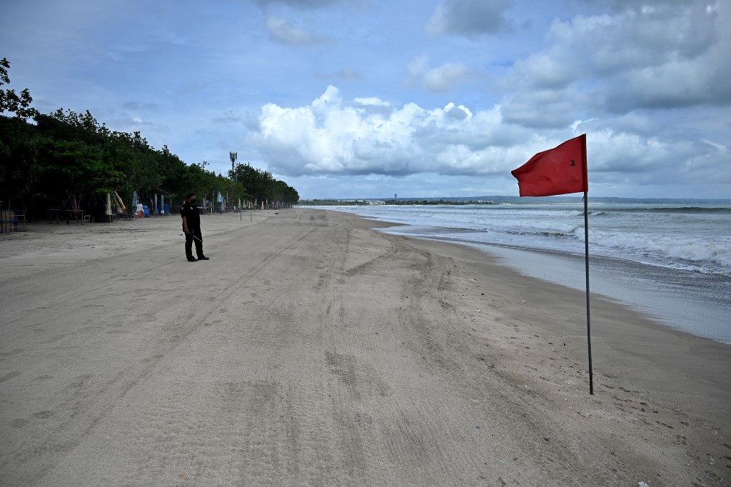 REOPENING. In this file photo, a Balinese security employee stand on a deserted beach amid the COVID-19 pandemic, in Kuta near Denpasar on Indonesia's resort island of Bali on May 29, 2020. File photo by Sonny Tumbelaka/AFP 