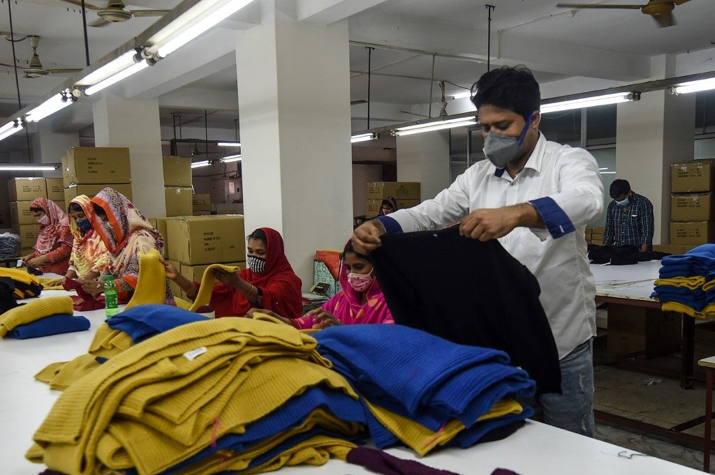GARMENTS. Dibbo Fashion owner Rubel Ahmed (R) inspects a sweater while laborers work at his garment factory in Savar, on the outskirts of Dhaka, Bangladesh, on June 18, 2020. Photo by Munir Uz Zaman/AFP 
