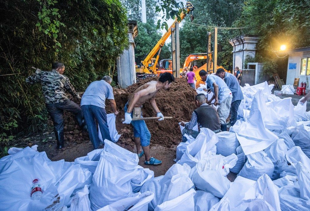 FIGHTING FLOODS. This photo taken on July 11, 2020 shows workers preparing anti-flood measures at a gate of a park along the Yangtze River in Wuhan in China's central Hubei province. Photo by AFP 