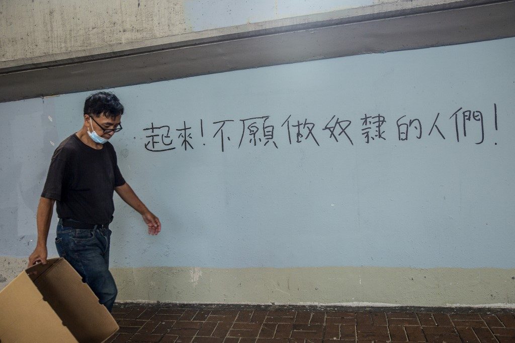 'REFUSE TO BE SLAVES.' A man walks past graffiti, a line from the Chinese national anthem that reads, 'Arise, ye who refuse to be slaves,' in Hong Kong on July 3, 2020. Photo by Isaac Lawrence/AFP 