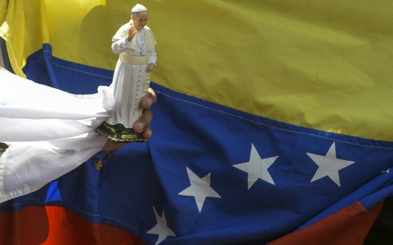 WORLD YOUTH DAY. A faithful holds a souvenir doll of Pope Francis next to a Venezuelan national flag, while gathering alongside the street to see him, during World Youth Day in Panama City on January 24, 2019. Photo by Raul Arboleda/AFP  