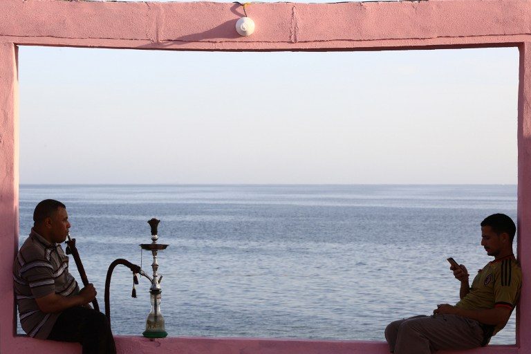 REFORMS COMING. Two men sit on wall overlooking the Red Sea at a popular cafe in the northwestern Saudi town of al-Wajh on April 25, 2016. Photo by Mohammed Al-Buhaisi/AFP 