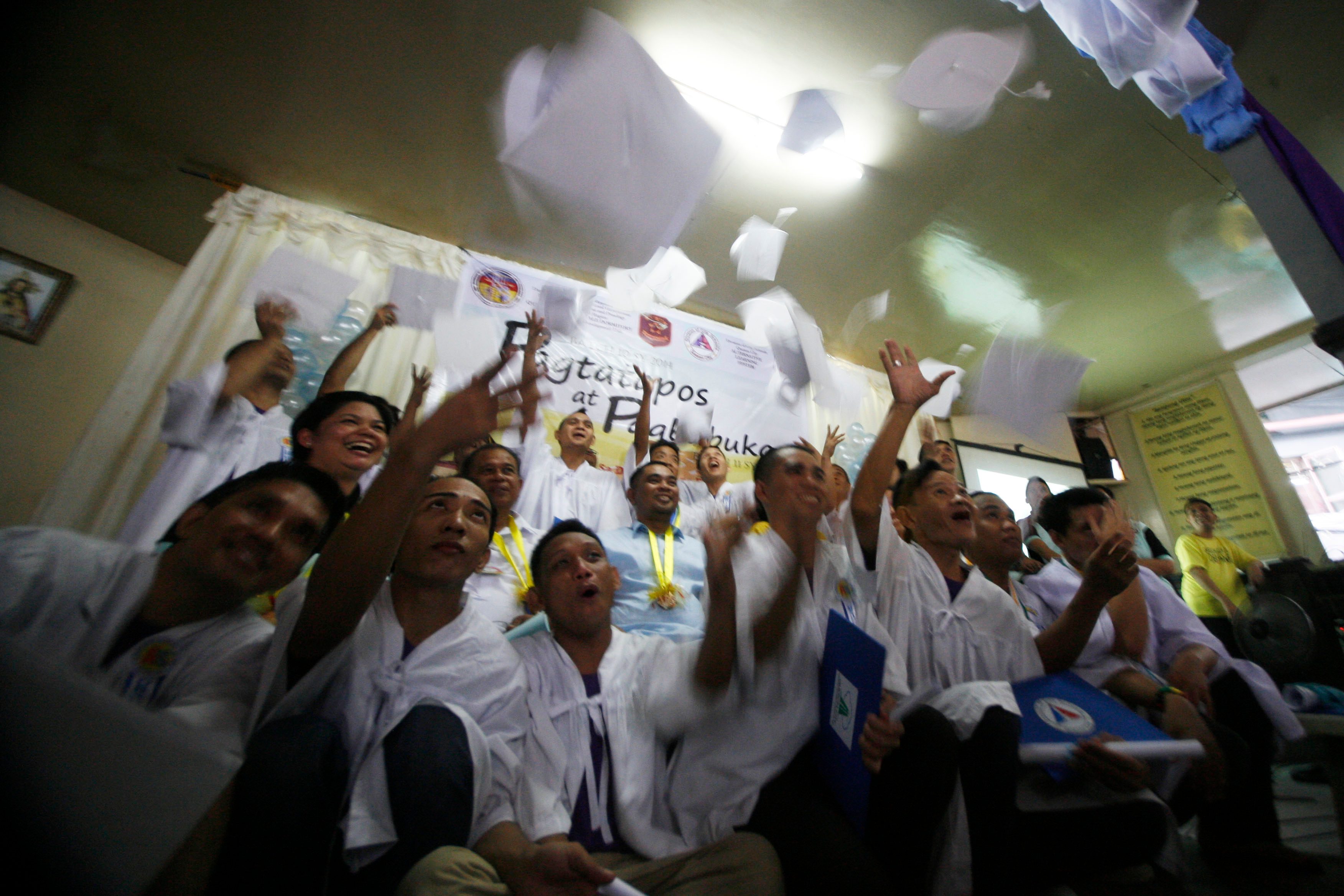 Detainees toss their toga caps during their graduation. 