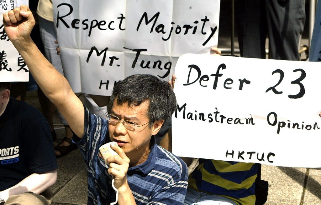 REJECT. A Member of the Hong Kong Trade Union Council holds placards and denounces the government's proposed national security bill in 2003. File photo by Peter Parks/AFP