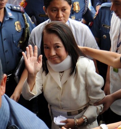 Former Philippine president Gloria Arroyo (C), surrounded by police officers, waves to photographers as she arrives to appear in court for her arraignment in Pasay City, February 23, 2012. AFP photo/Ted Aljibe