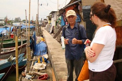 In this photograph taken on April 6, 2012 "Jakarta Hidden Tours" organizer Ronny Poluan (L) talks to tourists visiting a slum in North Jakarta. Poverty tourism is gaining ground in Indonesia with more tourists looking to "experience the real Jakarta". But while this is bringing more funds to the city's impoverished slum-dwellers, accusations of exploitation are not far behind. AFP PHOTO / LOIC VENNIN