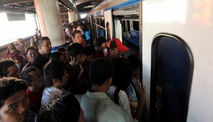 OVERCAPACITY. Commuters board the Manila Railway Transit (MRT 3) train along the main road of EDSA. The MRT 3 along with another privately-owned company MRT 2, and government-owned Light Railway Transit corporation (LRT) transport around half a million passengers a day combined. Photo by AFP