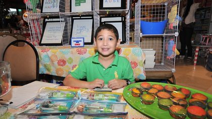 HAPPILY IN BUSINESS. A kiddo-preneur smiles from behind his desk of goodies for sale at the bazaar. (Photo courtesy of Maiki Oreta)