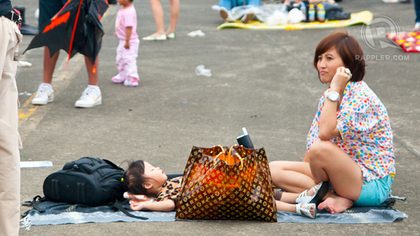SLEEPY. A Korean lady watches over her baby. Crowds bring mats and sit under the sea of kites.